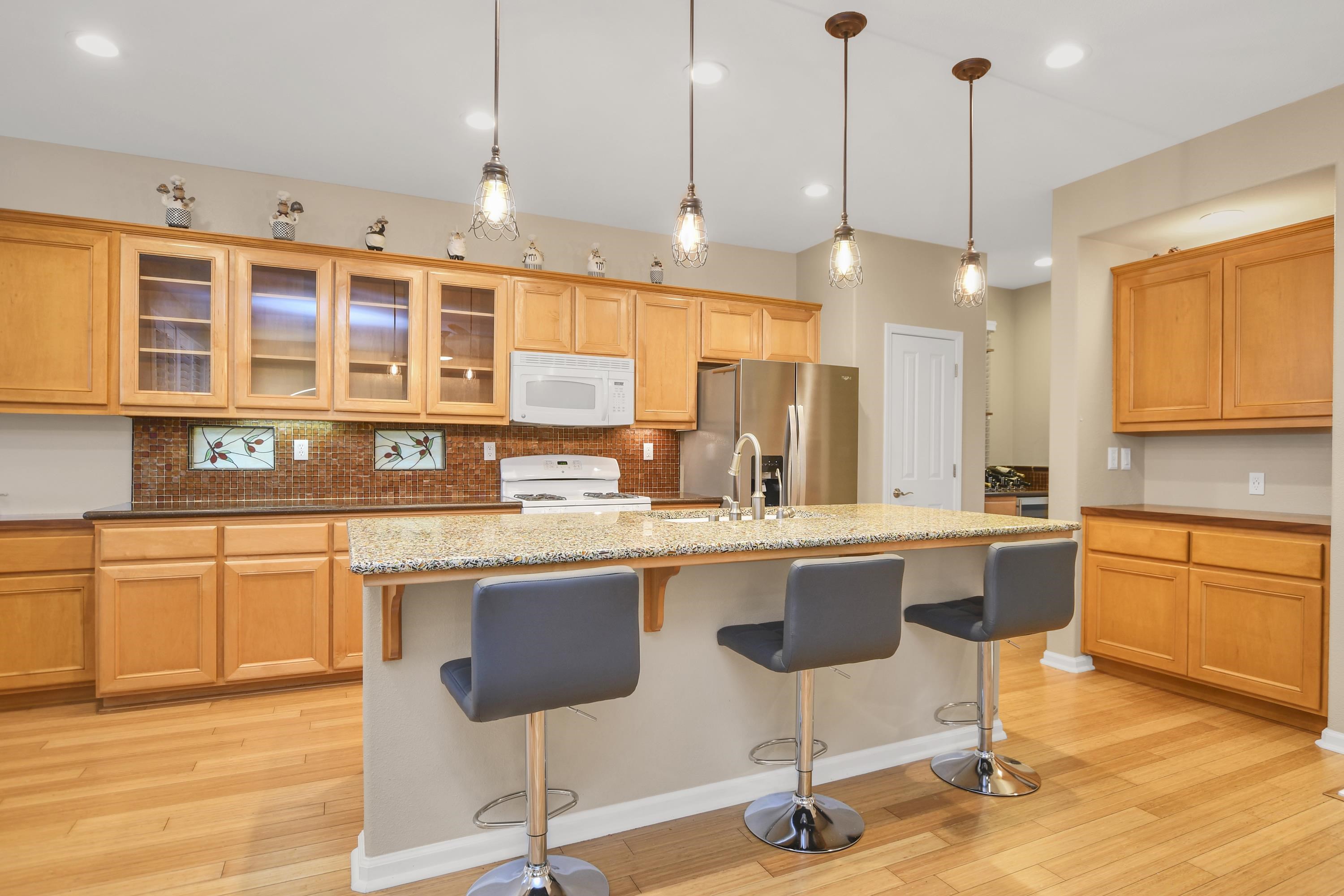 342 Desert Forest Court Rio Vista, CA 94571 - Photo 22 of 40 Kitchen featuring a kitchen breakfast bar, light wood-style floors, backsplash, white appliances, and glass insert cabinets