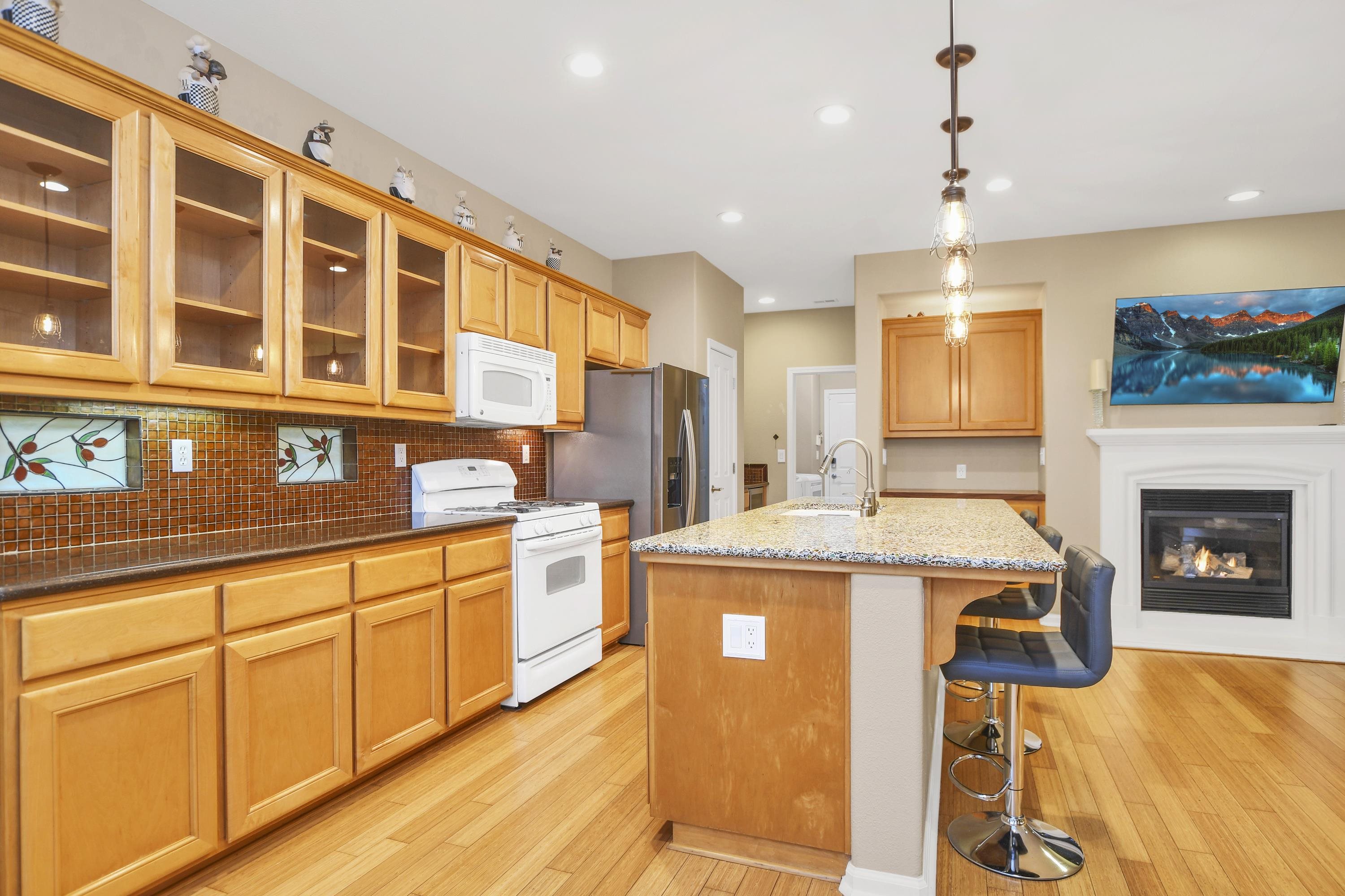 342 Desert Forest Court Rio Vista, CA 94571 - Photo 23 of 40 Kitchen featuring white appliances, glass insert cabinets, hanging light fixtures, a kitchen island with sink, and light stone counters
