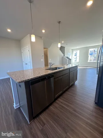 a kitchen with stainless steel appliances granite countertop a sink a counter space and wooden floor