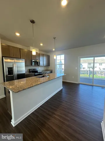 a large kitchen with stainless steel appliances a large counter top a stove and a wooden floors