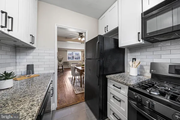 a kitchen with granite countertop a stove refrigerator and microwave