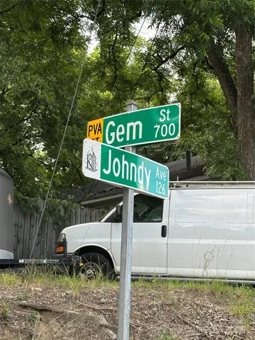 a view of a street sign under a large tree