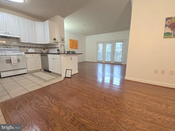 a kitchen with stainless steel appliances granite countertop a stove top oven a sink dishwasher and white cabinets with wooden floor
