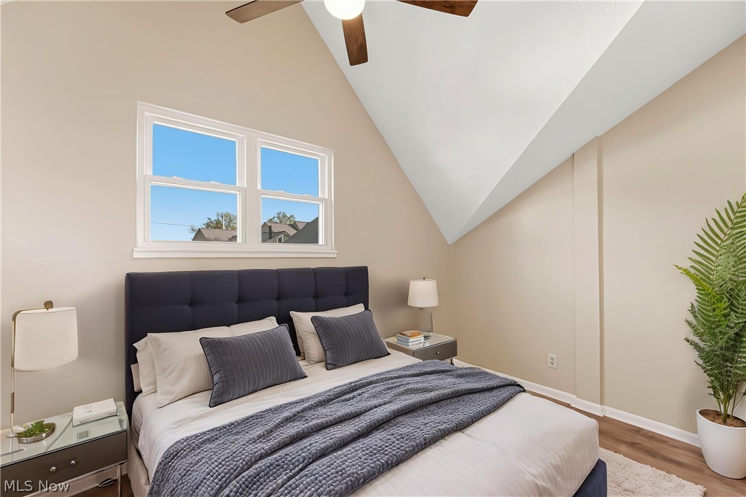 13011 West Lake Road Vermilion, OH 44089 - Photo 21 of 29 Vaulted ceiling room featuring a ceiling fan, dual windows, wood-finish flooring, and light-toned walls