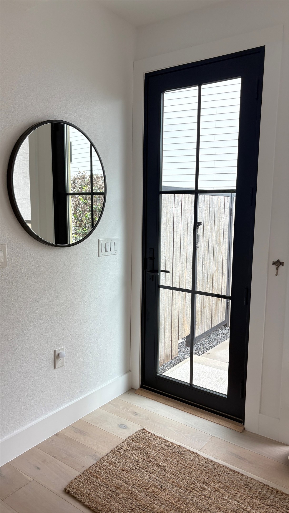 1816 Adina Street, Unit 2 Austin, TX 78721 - Photo 3 of 25 Black-framed glass-paneled door with dark hardware, white baseboards, light-toned wood-finish flooring, and white walls