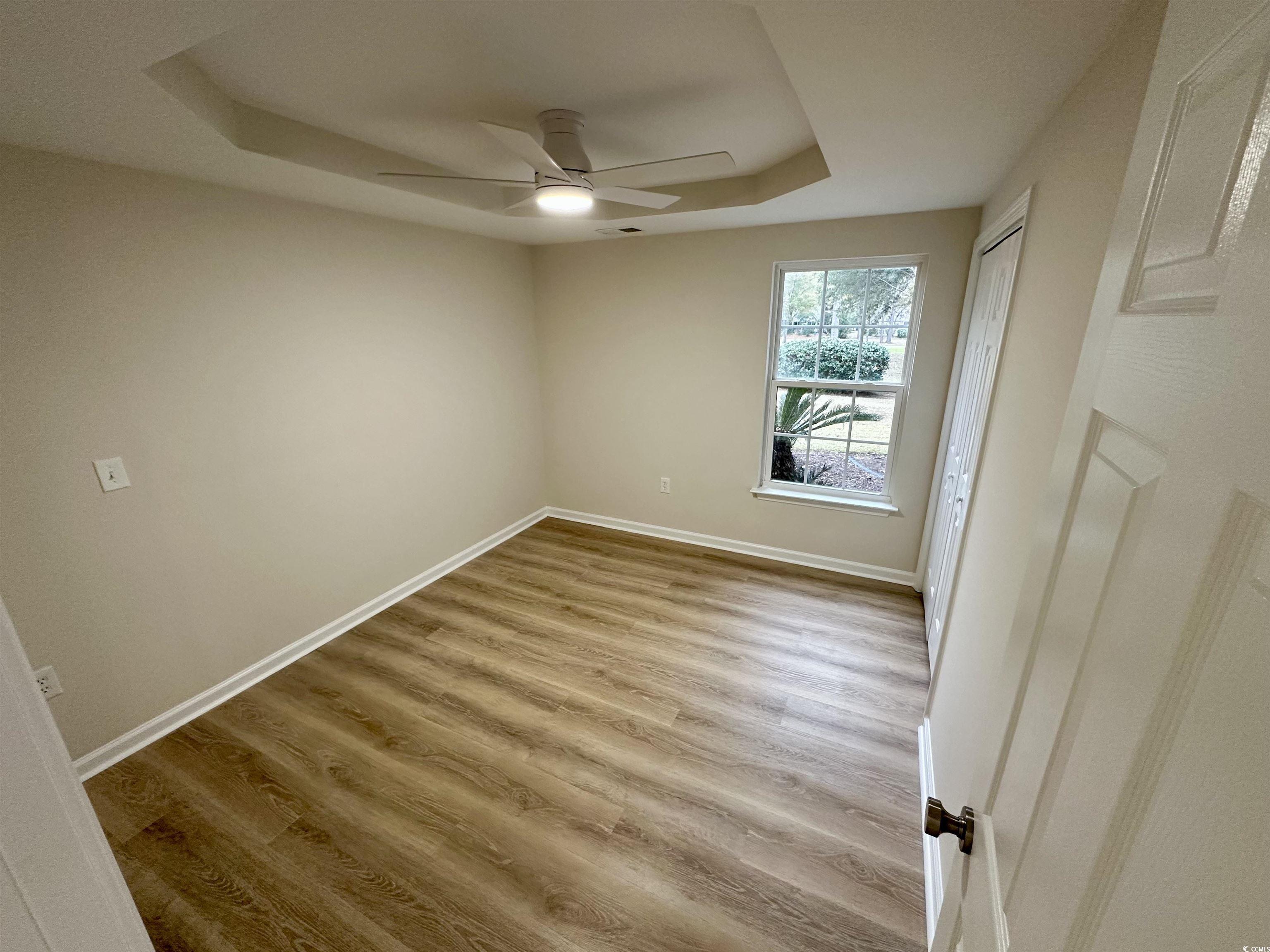 9 Pistachio Loop, Unit D Murrells Inlet, SC 29576 - Photo 16 of 21 Empty room featuring a raised ceiling, light wood finished floors, and a ceiling fan