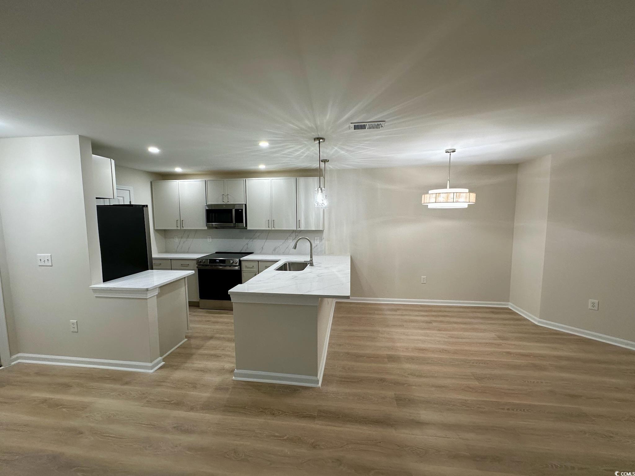 9 Pistachio Loop, Unit D Murrells Inlet, SC 29576 - Photo 2 of 21 Kitchen featuring stainless steel appliances, a peninsula, recessed lighting, decorative light fixtures, and light wood-type flooring