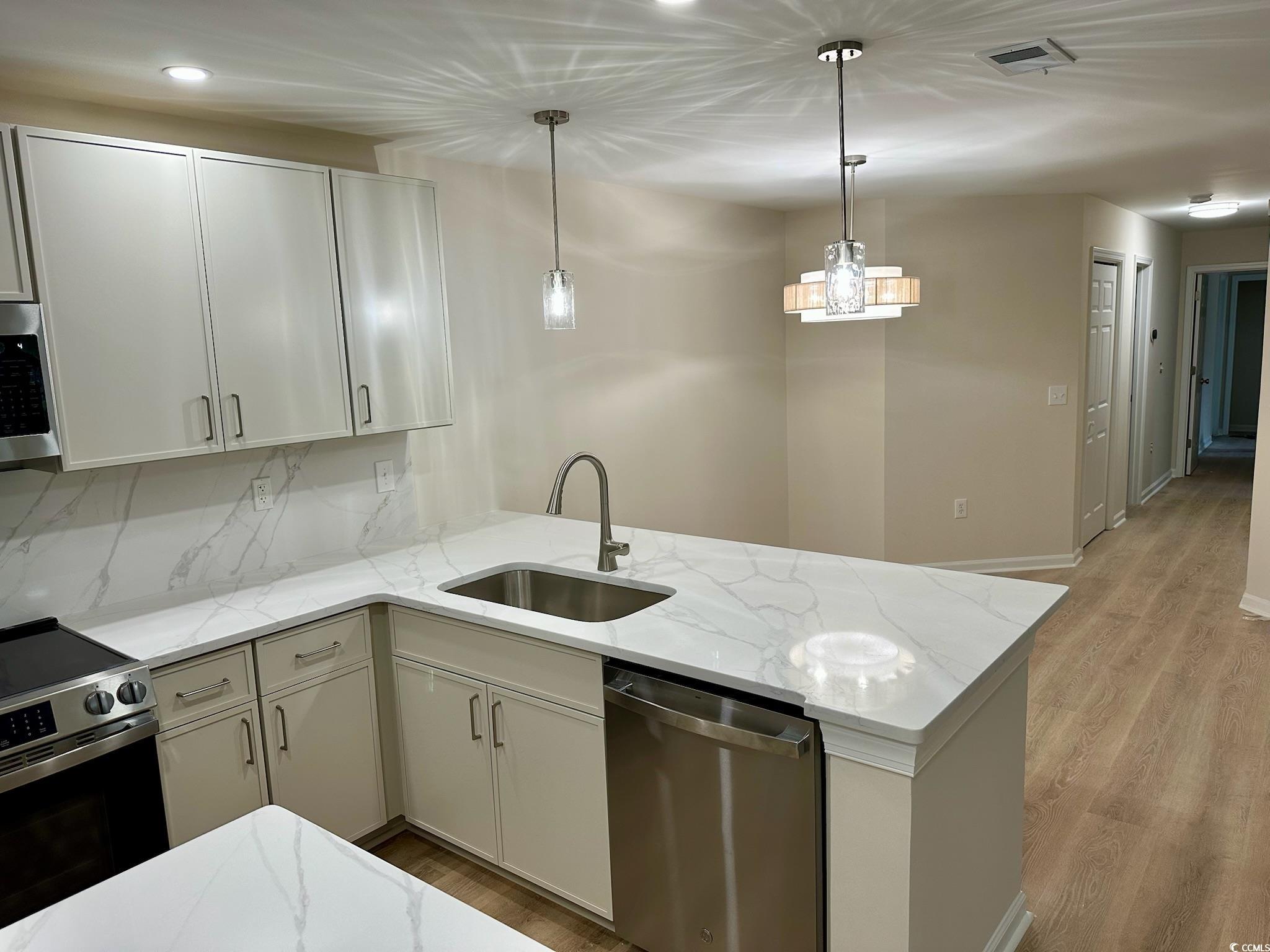 9 Pistachio Loop, Unit D Murrells Inlet, SC 29576 - Photo 3 of 21 Kitchen with stainless steel appliances, pendant lighting, light wood-style flooring, light stone counters, and a peninsula