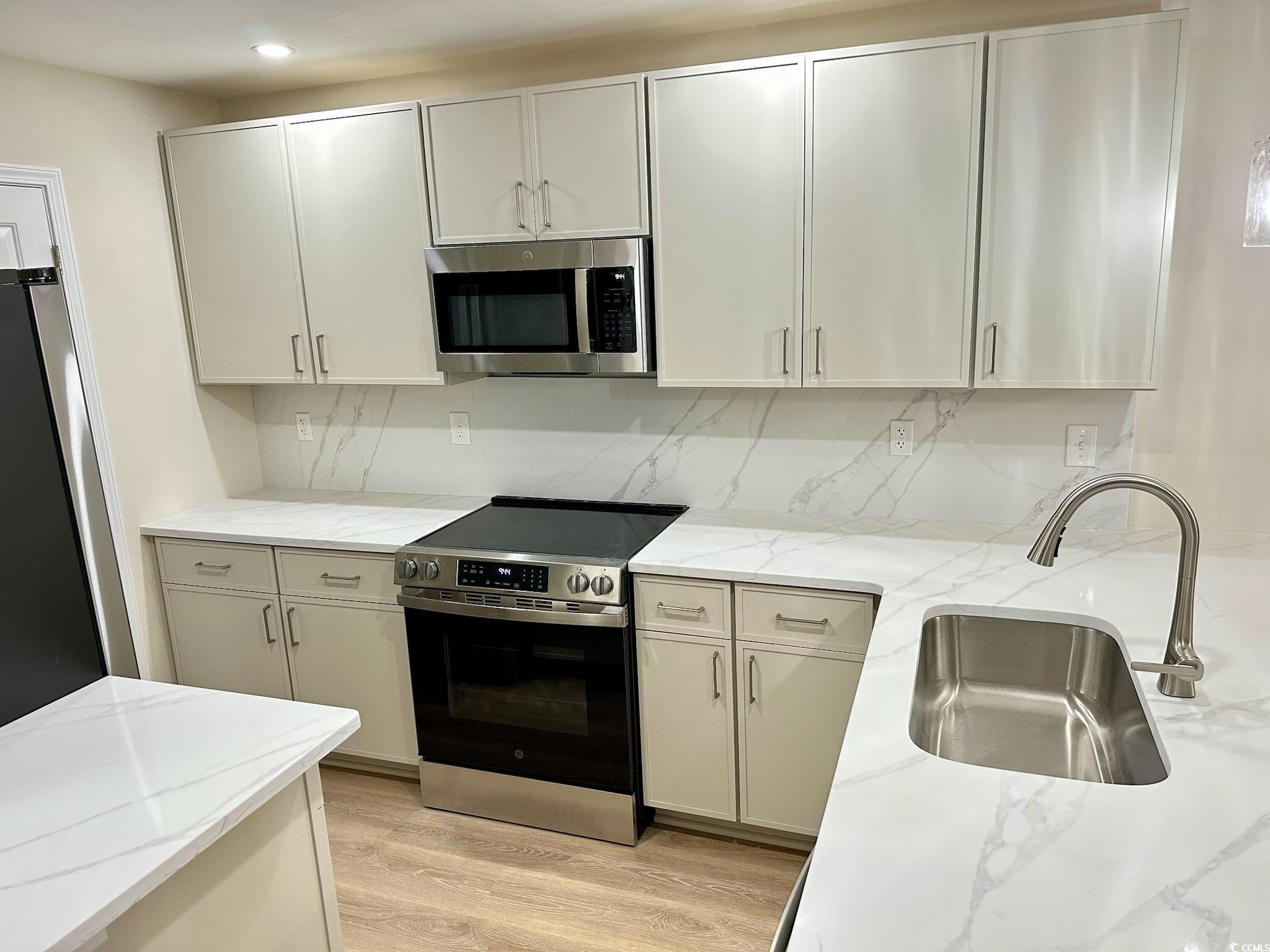 9 Pistachio Loop, Unit D Murrells Inlet, SC 29576 - Photo 5 of 21 Kitchen with stainless steel appliances, light wood-type flooring, light stone countertops, and backsplash