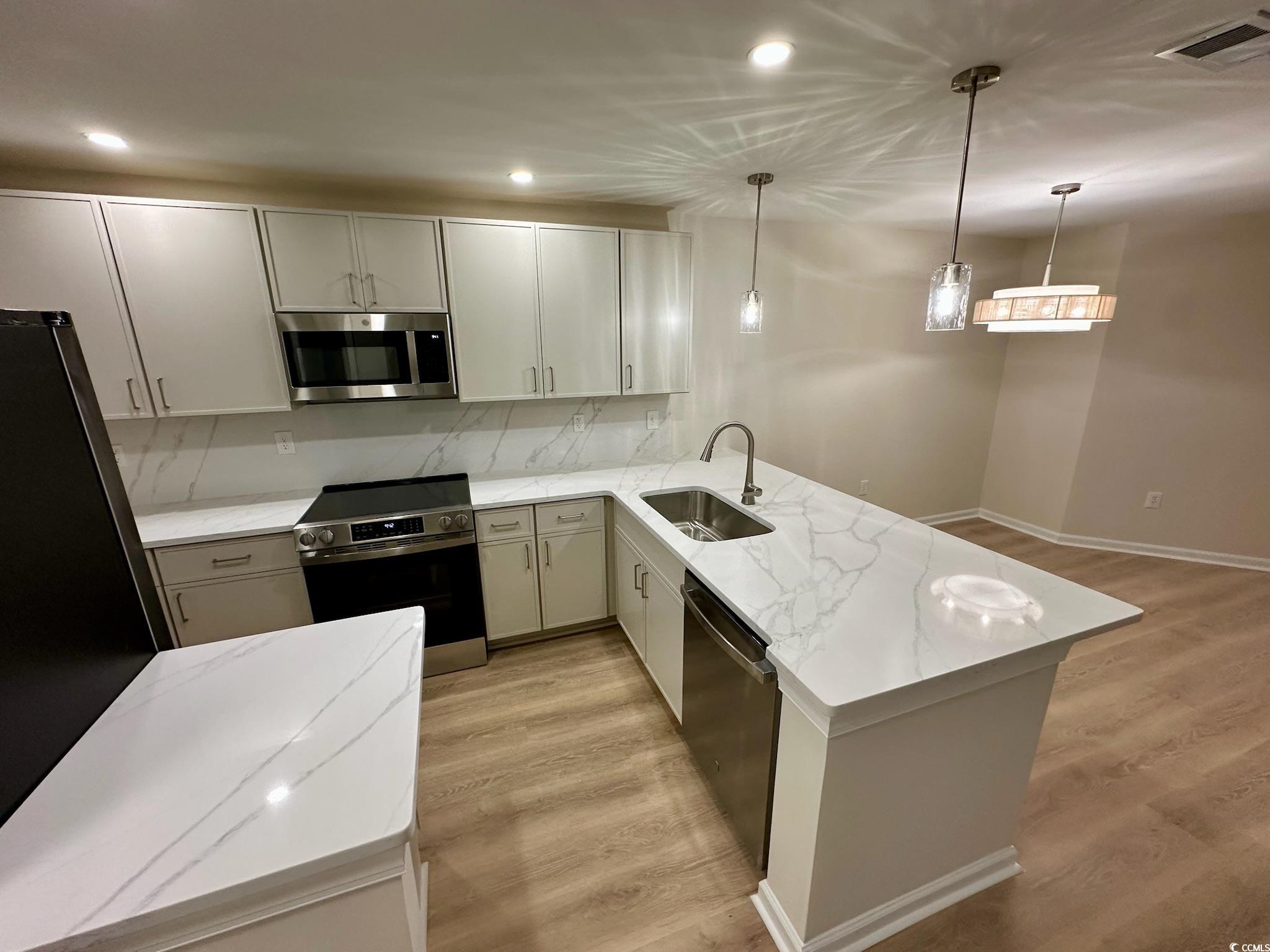 9 Pistachio Loop, Unit D Murrells Inlet, SC 29576 - Photo 6 of 21 Kitchen featuring light wood-style flooring, appliances with stainless steel finishes, decorative light fixtures, light stone countertops, and recessed lighting