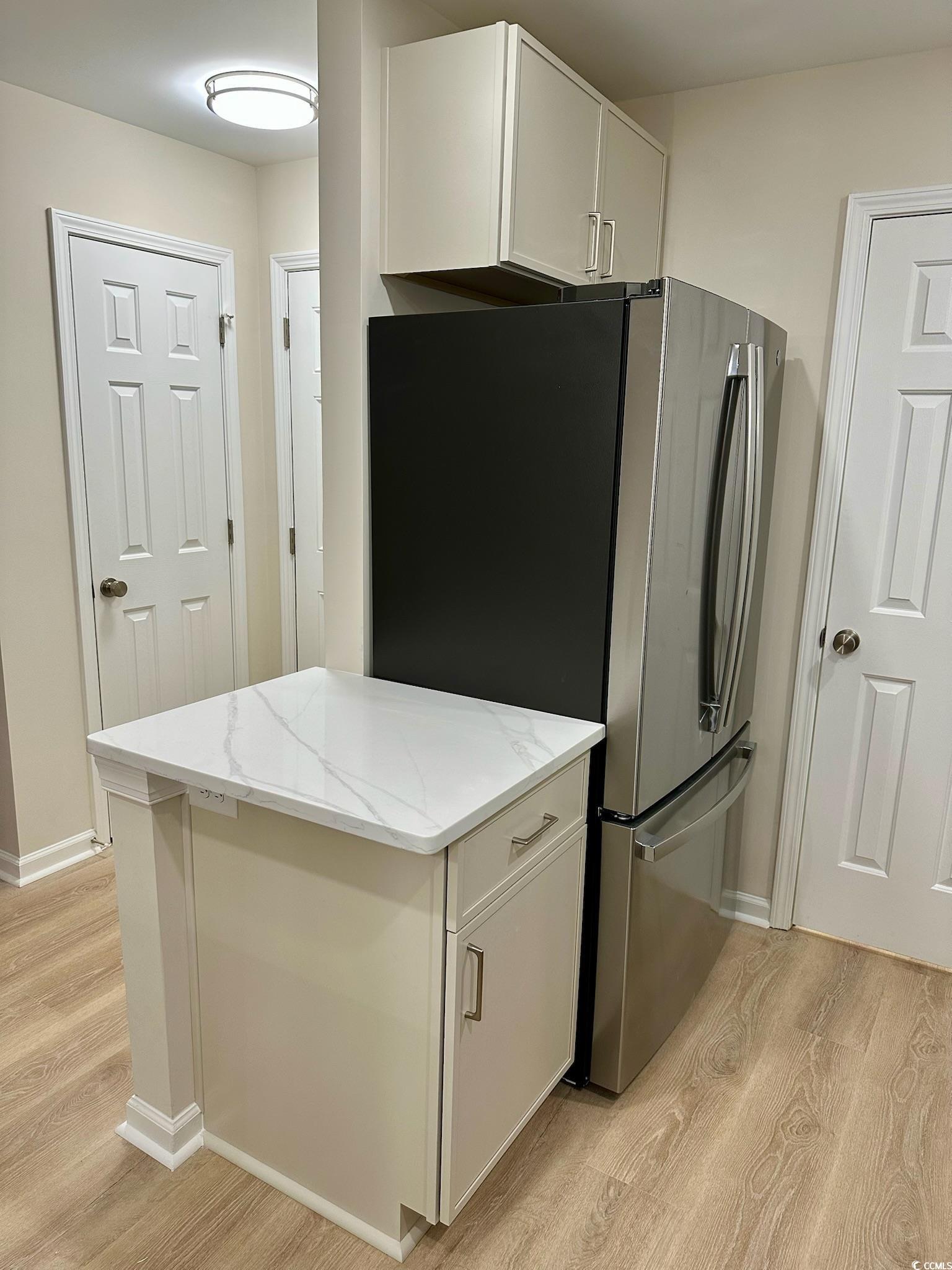 9 Pistachio Loop, Unit D Murrells Inlet, SC 29576 - Photo 7 of 21 Kitchen featuring light wood-type flooring, freestanding refrigerator, white cabinetry, and light stone countertops