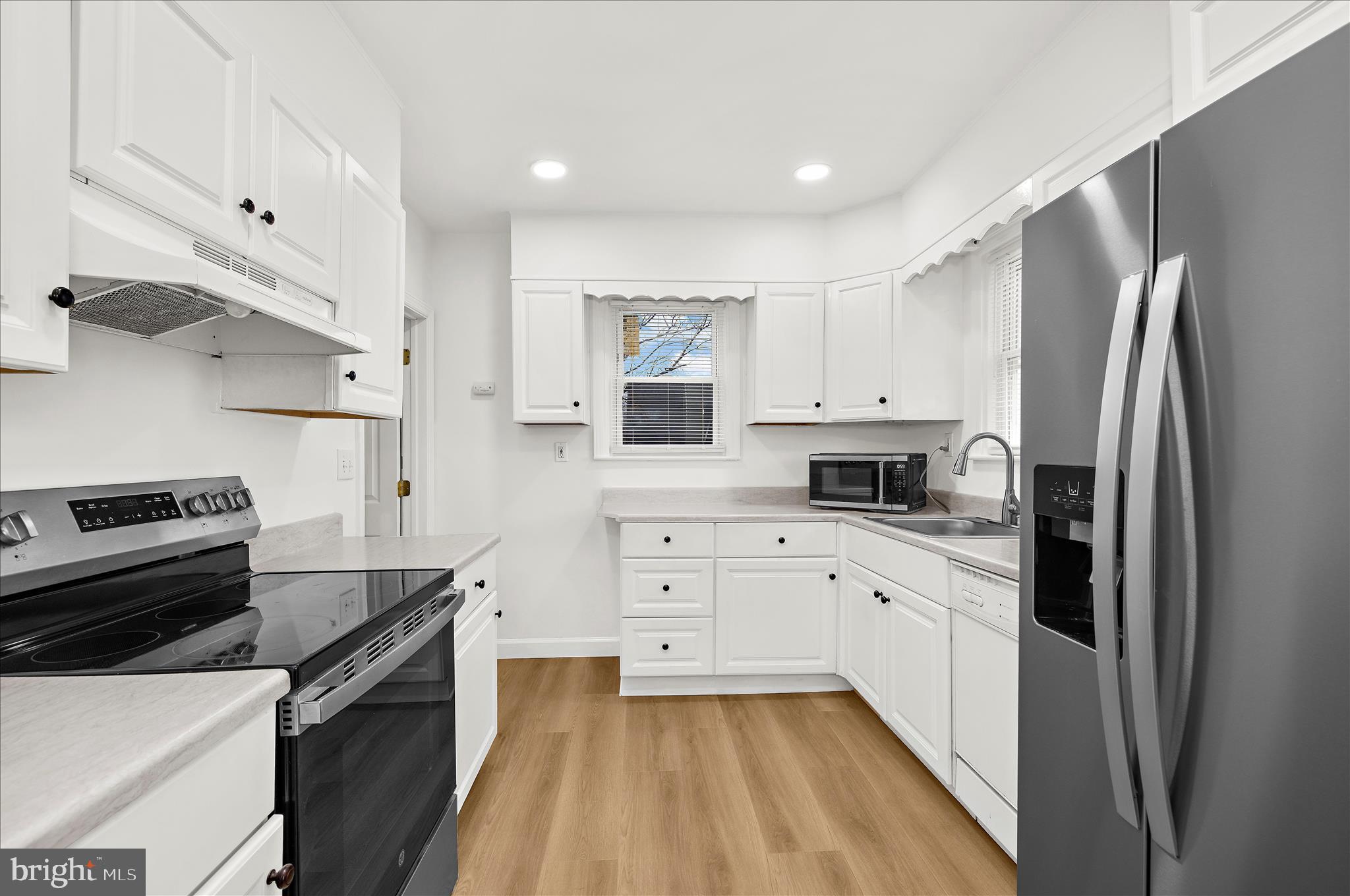 5701 Magie Street Baltimore, MD 21225 - Photo 13 of 49 a kitchen with white cabinets and stainless steel appliances