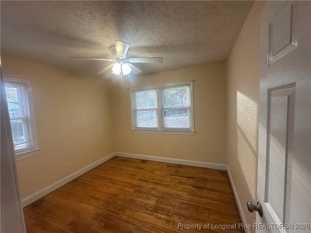 a view of empty room with wooden floor and fan