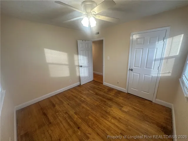 a view of empty room with wooden floor and fan