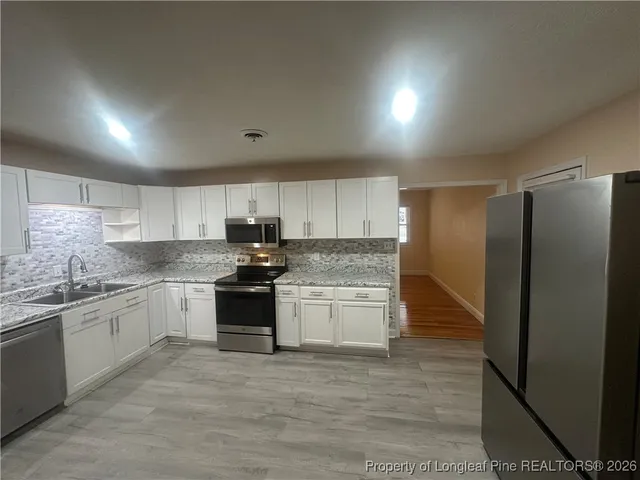 a large kitchen with stainless steel appliances granite countertop a stove a sink and a refrigerator
