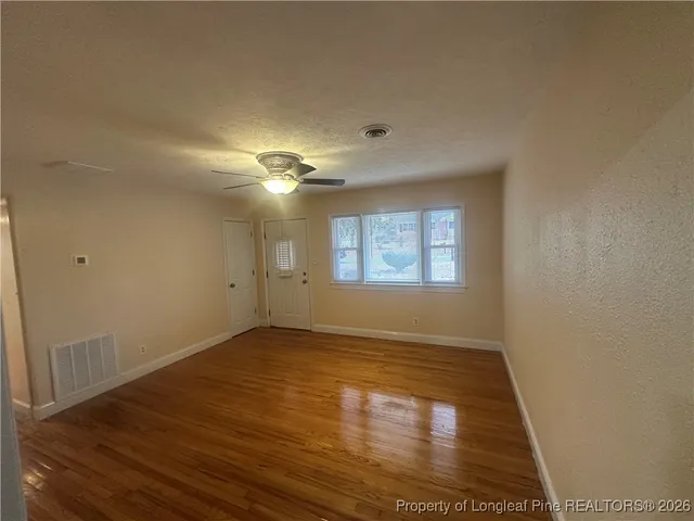 an empty room with wooden floor and windows