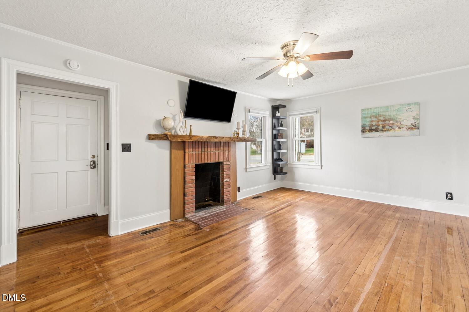 414 South Maple Street Graham, NC 27253 - Photo 3 of 42 a view of a livingroom with a fireplace a ceiling fan and wooden floor