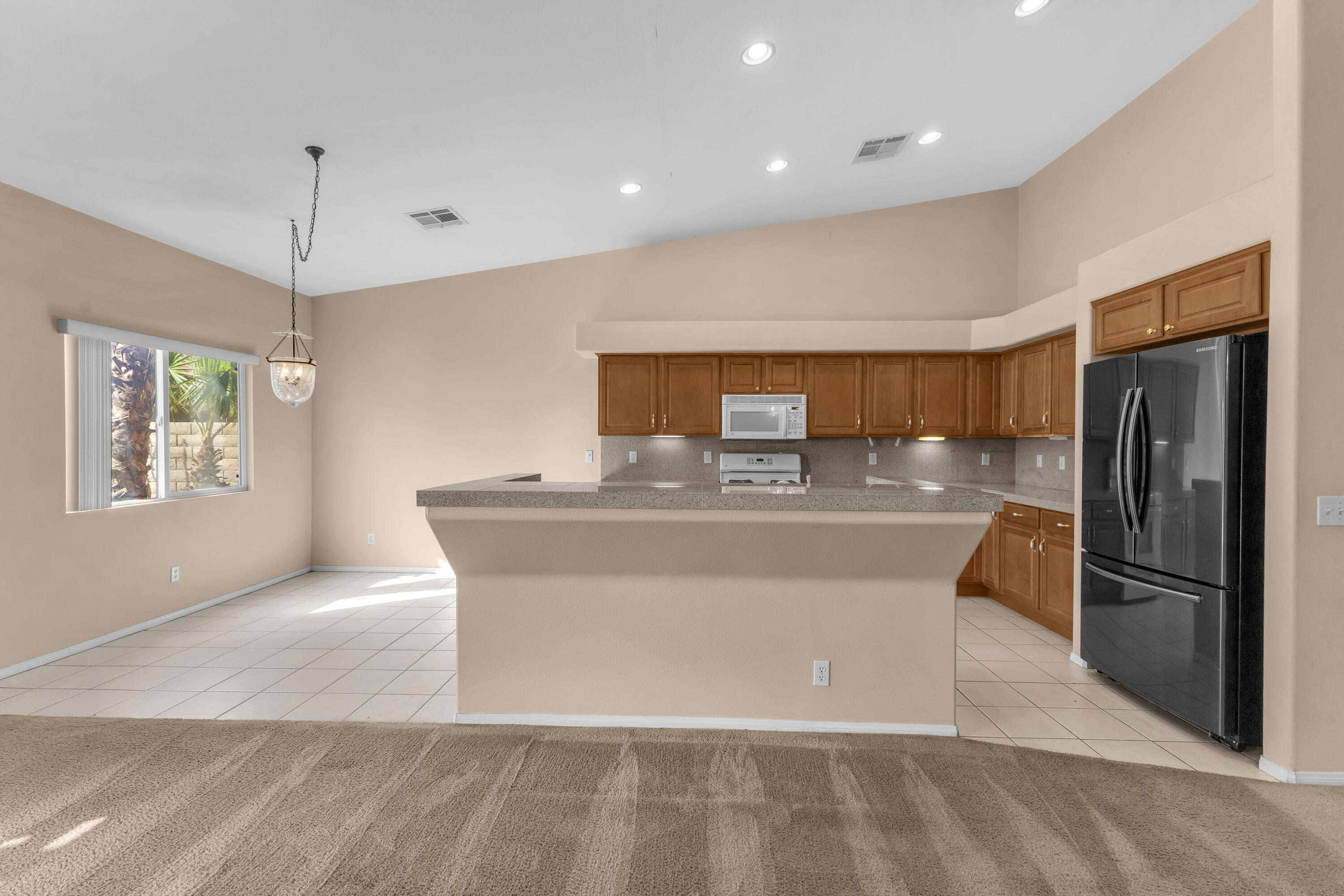 48690 Hepburn Drive Indio, CA 92201 - Photo 15 of 36 a view of kitchen with stainless steel appliances granite countertop a refrigerator a sink dishwasher with a dining table and chairs