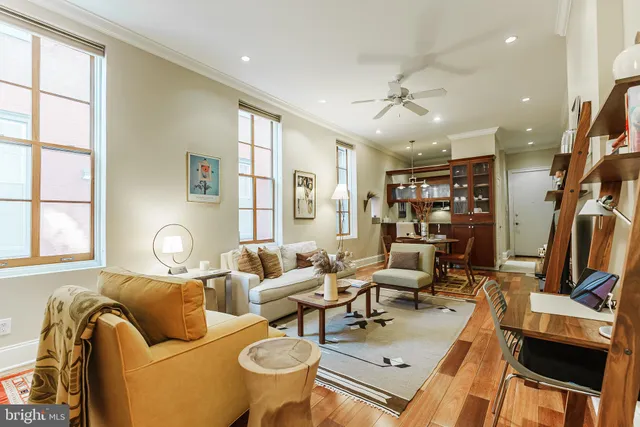 a living room with furniture two window and a flat screen tv