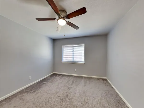 an empty room with a window and ceiling fan