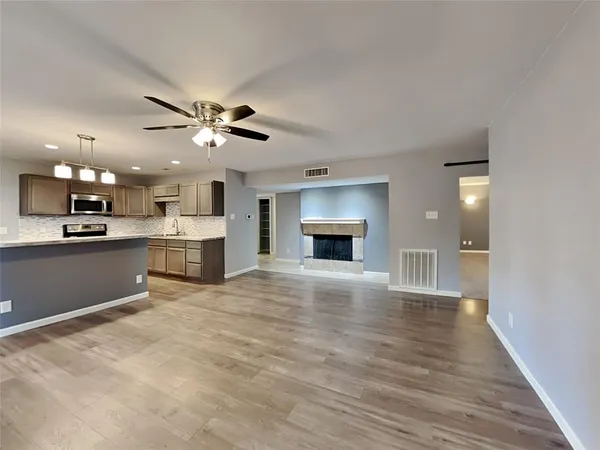a view of an empty room with kitchen and a window