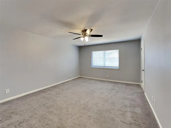 an empty room with a window and a ceiling fan