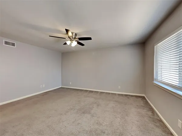 an empty room with a window and a ceiling fan