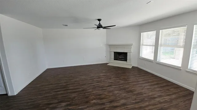 an empty room with windows fireplace and fan