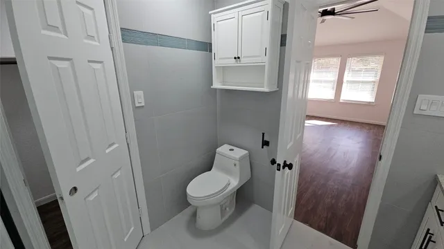 a white toilet sitting in a bathroom next to a window
