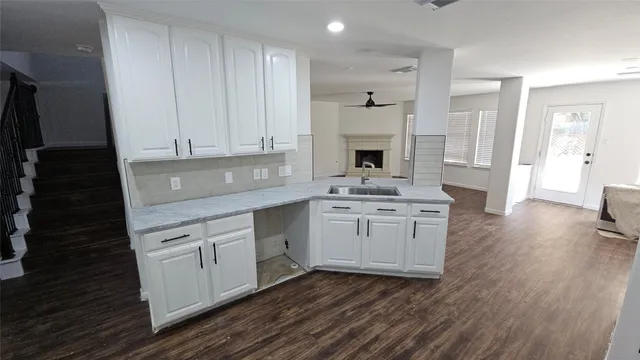 a kitchen with granite countertop a sink cabinets stainless steel appliances and wooden floor