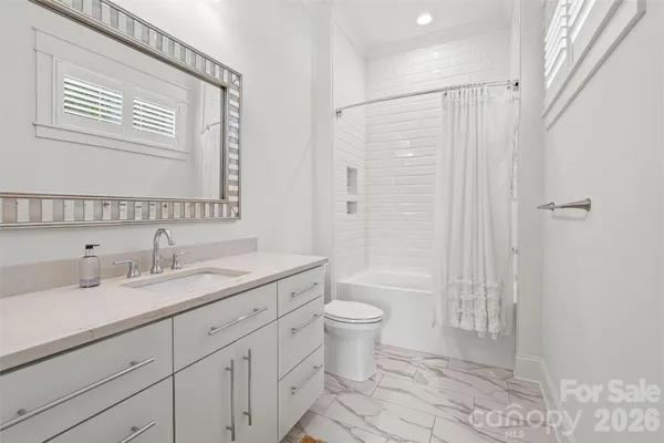 a bathroom with a granite countertop sink toilet a mirror a vanity and shower