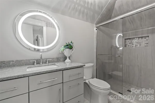 a bathroom with a granite countertop toilet a sink and a mirror