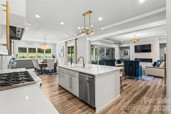 a large kitchen with stainless steel appliances a stove center island a window and living room view