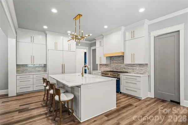 a kitchen with kitchen island a stove a table and chairs in it
