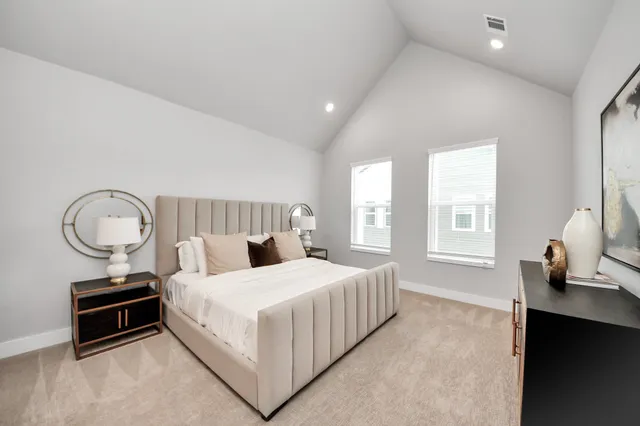 a bedroom with a bed a dresser and windows