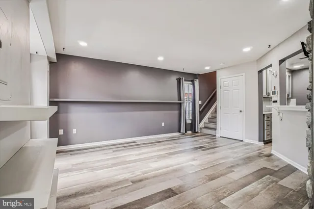 a view of an empty room with wooden floor and a ceiling fan