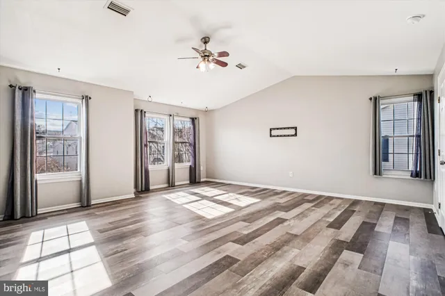 a view of an empty room with window and wooden floor