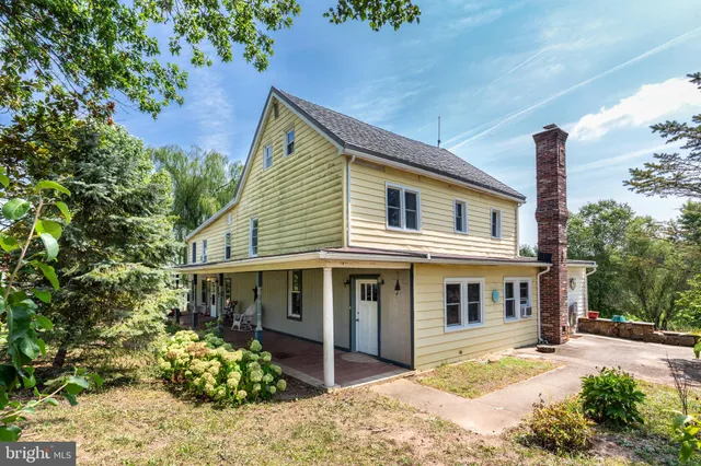 a view of a white house next to a yard with potted plants