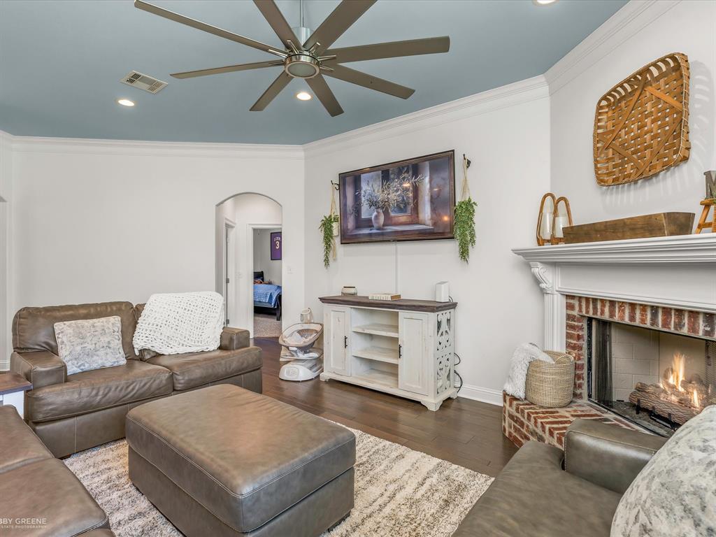 690 Lessie Drive Stonewall, LA 71078 - Photo 7 of 29 Living room featuring a brick fireplace with a white mantel, tray ceiling with recessed lighting and a ceiling fan, and dark wood-finish flooring
