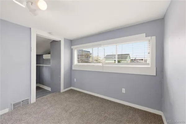 an empty room with kitchen area and windows