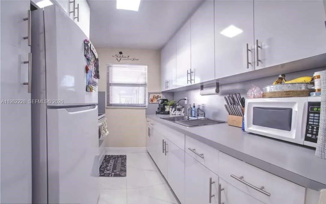 1325 West 68th Street, Unit 113 Hialeah, FL 33014 - Photo 6 of 14 a kitchen with stainless steel appliances a refrigerator and cabinets