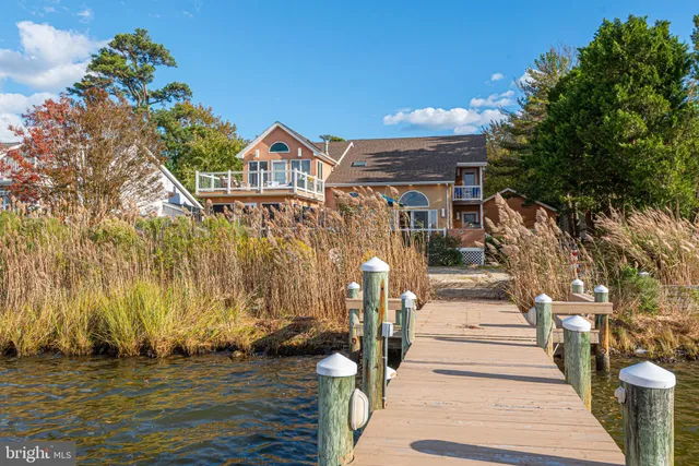 a kitchen with stainless steel appliances granite countertop a refrigerator a sink dishwasher a stove and white countertops with wooden floor