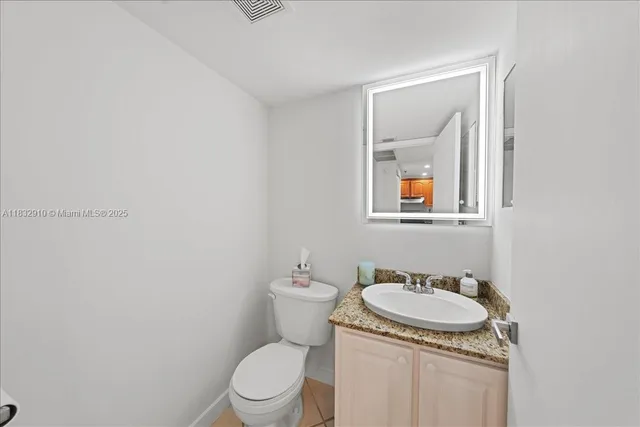 a bathroom with a granite countertop toilet and a sink