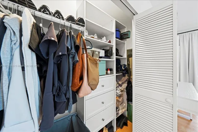 a view of walk in closet with clothes and shoes
