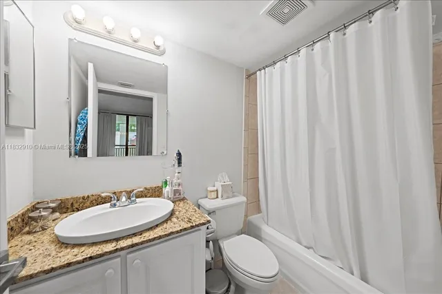 a bathroom with a granite countertop sink toilet and mirror