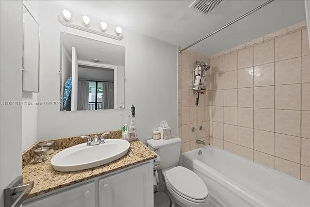 a bathroom with a granite countertop sink toilet a mirror and shower