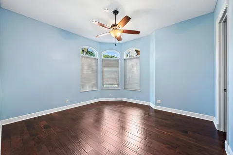 a view of an empty room with window and chandelier fan