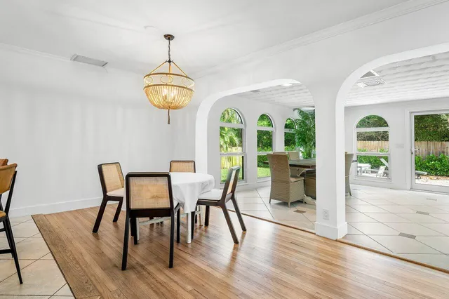 a dining room with wooden floor a chandelier a glass table and chairs