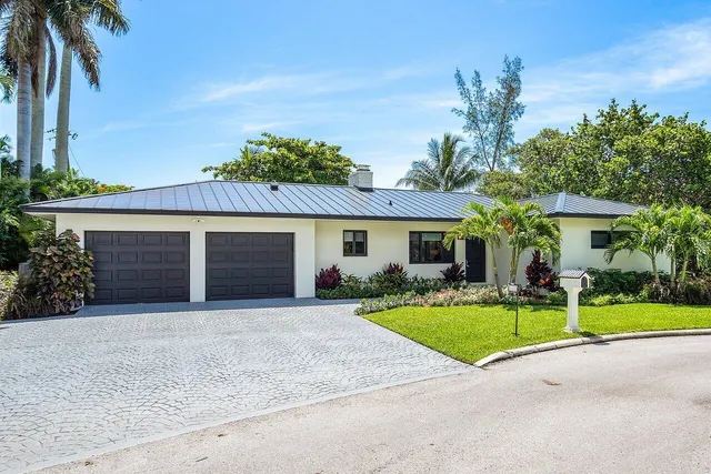 front view of a house with a yard and palm trees