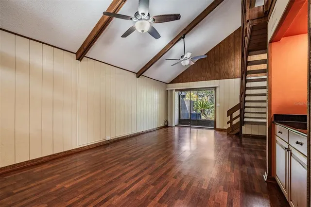a view of empty room with wooden floor and fan